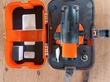 une mallette orange contenant des outils, posée sur un plancher en bois