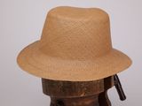 un chapeau de paille posé sur un support en bois, sur fond blanc