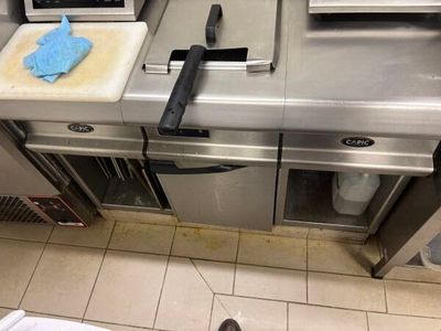 une personne debout devant un plan de travail de cuisine, avec un couteau et une planche à découper