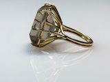 a close up of a gold ring with a large gray stone