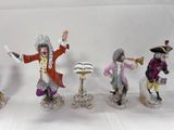 four figurines of a man with a trumpet, a woman with a hat, a man with a cane, and a woman with a hat