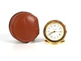 une petite horloge posée à côté d'un étui en cuir