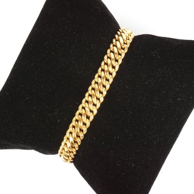 un bracelet en chaîne d'or posé sur un coussin en velours noir
