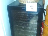 a small black refrigerator with a basket on top of it next to a broom