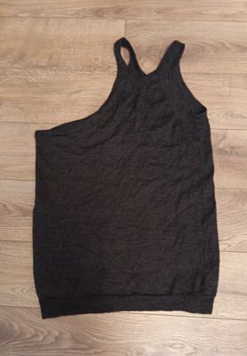 a black tank top on a wooden floor next to a pair of shoes