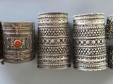 Plusieurs bracelets en argent sont disposés en rangée sur une étagère