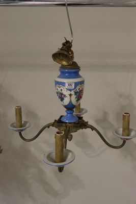un vase bleu et blanc suspendu à un lustre en laiton