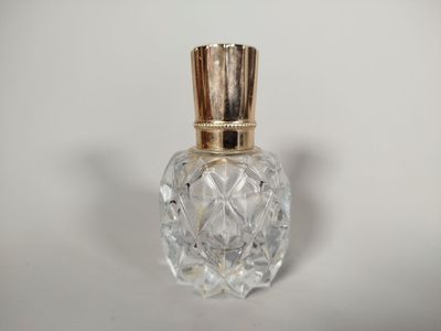 une image représentant une bouteille en verre avec un bouchon doré, posée sur une surface blanche