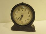 une petite horloge posée sur une table blanche