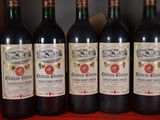 six bottles of red wine are lined up on a shelf