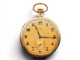une vieille montre de poche en or posée sur une surface blanche, sur fond blanc