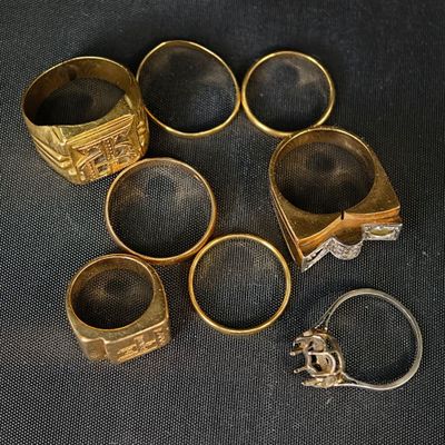 plusieurs bagues en or et une bague en argent posées sur un tissu noir