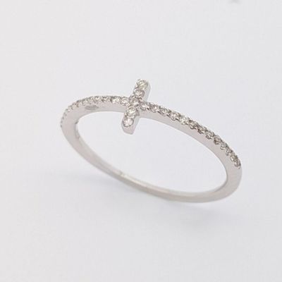un gros plan d'une bague en forme de croix sertie de diamants sur une surface blanche