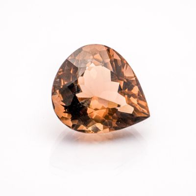 a close up of a faceted brown diamond on a white surface