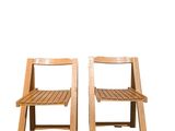 two wooden chairs sitting next to each other on a white surface