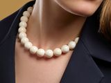close up of a woman wearing a necklace with a pearl bead