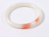 an orange and white bracelet on a white surface with a white background