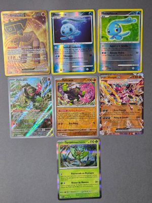 Plusieurs cartes Pokémon différentes sont posées sur une table dans une pièce.
