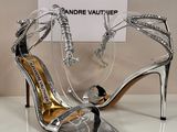 des sandales à talons hauts argentées et noires exposées devant une pancarte