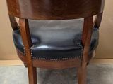 a wooden chair with a black leather seat in a room