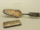 une cuillère en argent et un petit objet en métal posés sur une table