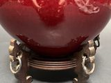 a red vase sitting on top of a metal stand