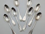 six silver spoons are arranged in a circle on a table