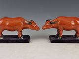 deux figurines représentant des taureaux aux cornes dressées, posées sur un socle noir