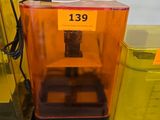une imprimante 3D jaune et orange posée sur une table à côté d'autres imprimantes 3D jaunes et noires