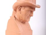 a clay bust of a man with a hat on