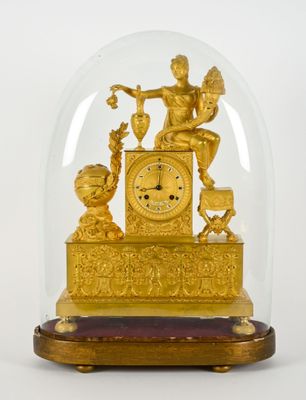 une horloge en or sous un dôme de verre sur une table