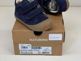des chaussures bleues de petit garçon dans une boîte posée sur une surface blanche