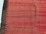 a close up of a red and black rug on a white wall