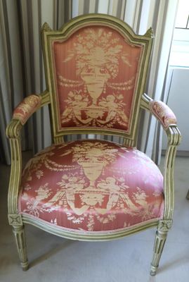 a chair that has a pink and gold upholstered back