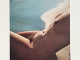 une photo d'une femme nue allongée sur une plage au bord de la mer
