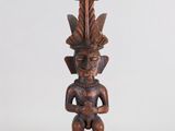une statue en bois représentant un homme avec une plume sur la tête