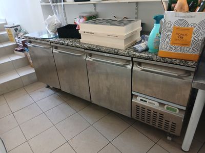 une cuisine équipée d'un plan de travail en inox et d'un réfrigérateur