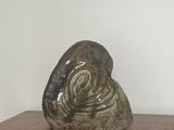 une sculpture en céramique représentant un escargot, posée sur une table en bois