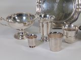 many silver dishes and cups on the table