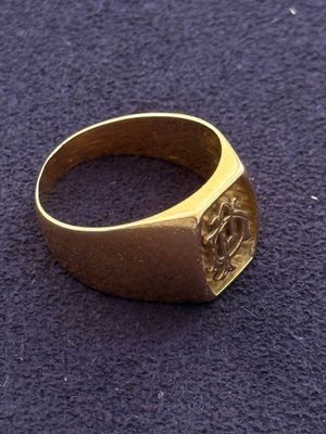 a close up of a gold signet ring on a purple surface