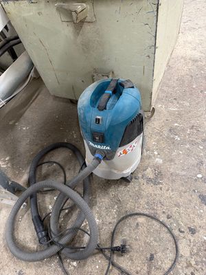 un aspirateur bleu et noir posé par terre à côté d'une poubelle