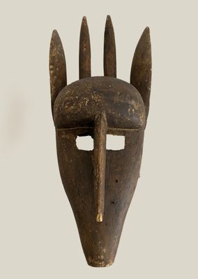 an old wooden mask with horns on it ' s face