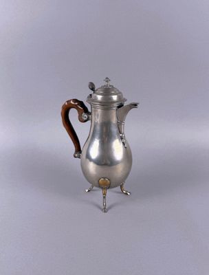 an antique silver coffee pot with a wooden handle on a stand