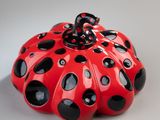 red and black ceramic pumpkin with black dots and a bow on top