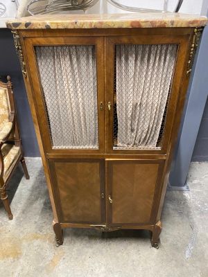 a cabinet with curtains on top of it next to a chair