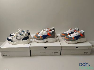 trois paires de baskets sont posées sur une boîte