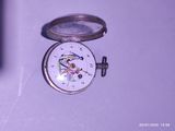 une petite montre de poche en argent sur laquelle est représenté un oiseau