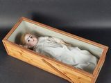 a small doll in a wooden box on a table