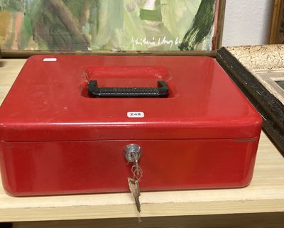 une boîte métallique rouge posée sur une table, contenant une clé
