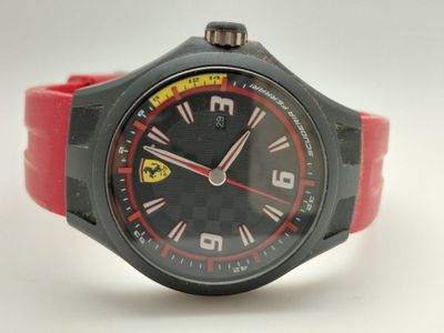 La montre est noire et rouge, avec un bracelet en caoutchouc rouge.
